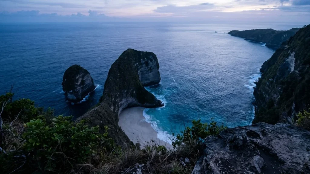 Nusa Penida vs Nusa Lembongan day trip — Kelingking Beach cliff viewpoint at early morning with T-Rex rock formation descending to white sand beach below.